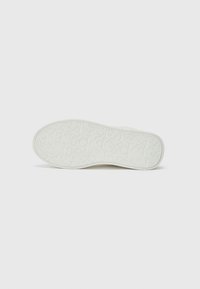 White rubber sneaker sole with embossed brand letters and a textured pattern. Curved shape and smooth surface, minimalistic design.