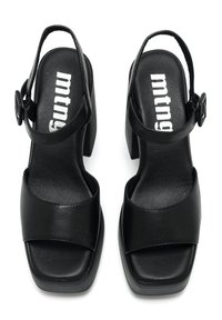 Sandalias negras de tacón bloque con una amplia tira frontal y tira ajustable en el tobillo, fabricadas en material sintético liso. Logotipo visible en la plantilla.