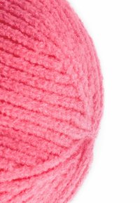 Pelote de fil rose avec une texture douce et fluff, présentant un design en spirale et une apparence lisse et uniforme.