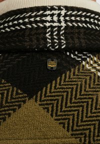 Gebreide trui met een geometrisch patroon in zwart, wit en olijfgroen. Heeft een crèmekleurige kraag en een PME Legend logo label.