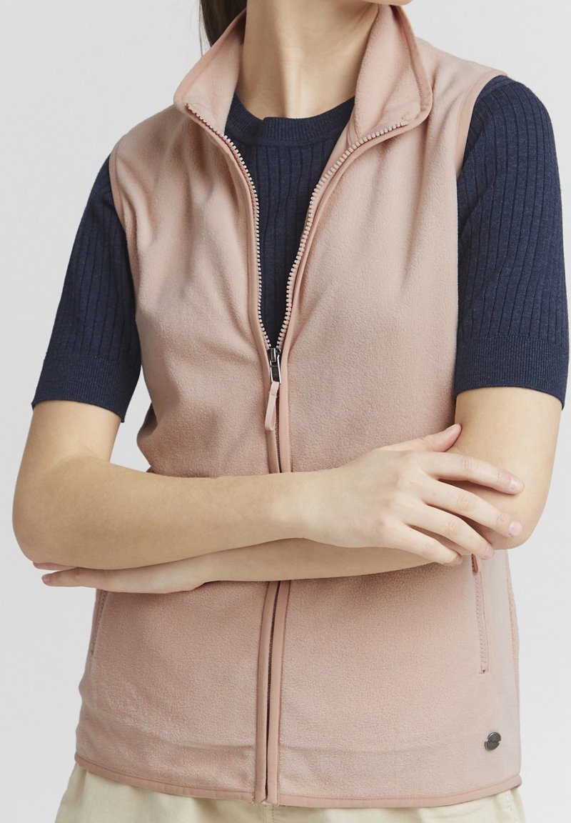 Ljusrosa fleeceväst med dragkedja fram, ståkrage, sidofickor och ribbade navy ärmar. Mjuk textur, avslappnad design.