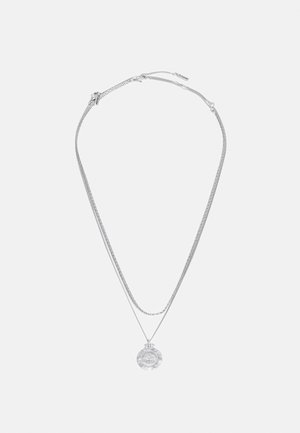 Collier en argent avec deux chaînes présentant des motifs élaborés et un pendentif circulaire affichant un design détaillé.