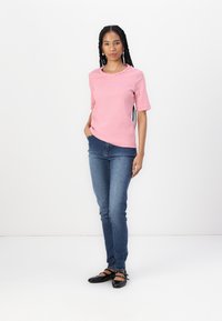 Striped red and white t-shirt, short sleeves, round neck, paired with blue skinny jeans and black strap shoes. Plain white background.