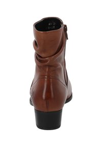 Botín de cuero marrón hasta el tobillo con puntera redondeada, diseño arrugado y un pequeño tacón negro. Cuenta con una cremallera lateral para facilitar su uso.