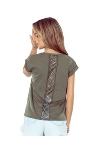 Oliwkowa koszulka z krótkimi rękawami, z koronkowym wstawieniem na plecach w geometryczny wzór. Materiał wydaje się miękki i lekki.