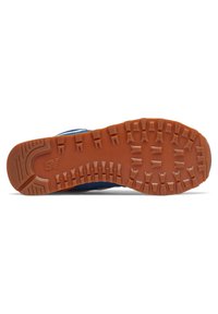 Semelle d'une sneaker bleue avec une épaisse semelle en caoutchouc orange présentant des grips rectangulaires et en trapèze, ainsi qu'un logo New Balance.