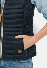 Marine puffer vest met een ritssluiting, horizontale stiksels en een zijvak. Geaccentueerd met een klein, bruin logo-op een patch.
