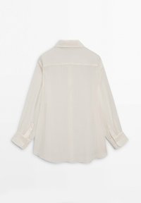 Chemise crème à manches longues avec poignets boutonnés et col classique, vue de dos sur un fond blanc.