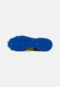 Trailrunning-Schuhsohle mit einer leuchtend blauen Gummisohle, ausgestattet mit aggressiven Profilstollen und einer strukturierten Oberfläche für besseren Halt.