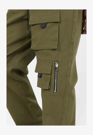 Cargo bukser i olivengrøn, med flere lommer, en lynlåslomme på siden og en snor i taljen. Materialet fremstår holdbart og tekstureret.