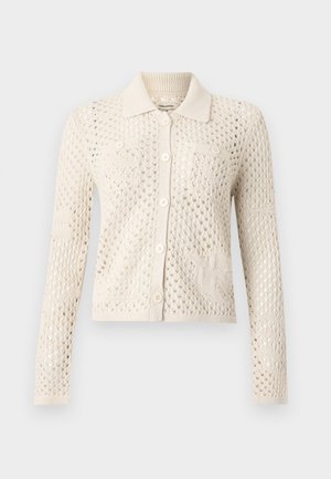 Ζακέτα από πλεκτό σε κρεμ χρώμα με μακριά μανίκια, σχέδιο ανοιχτού πλέγματος, μυτερό γιακά, κλείσιμο με κουμπιά μπροστά και δύο τσεπάκια στο στήθος με κουμπιά.