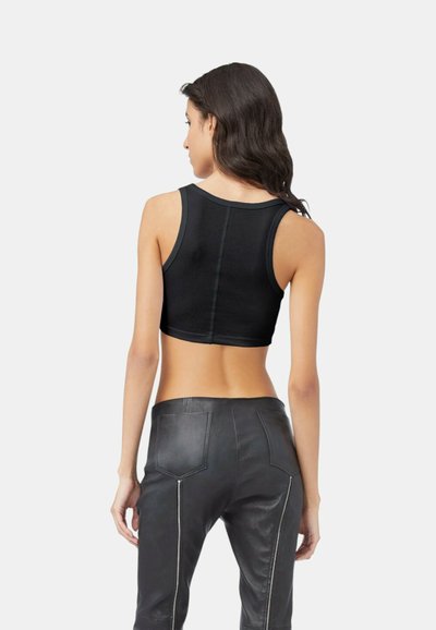Top tank nero corto realizzato in tessuto elasticizzato, con scollatura rotonda e dettagli di cucitura definiti, abbinato a pantaloni in pelle nera.