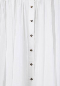White dress with a vertical button placket, featuring round bronze buttons and textured fabric. Designed with a loose, flowing shape.