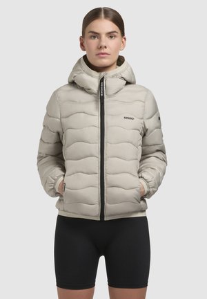 Lichtbeige pufferjack met een gepatternde textuur, ritssluiting en een capuchon. Kenmerken zijn onder andere elastische manchetten en een logoaccent op de borst.