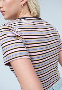 Gestreept T-shirt van zachte stof; heeft roze, blauwe, gele en zwarte strepen; korte mouwen; aangesloten ontwerp; ribbeltextuur.