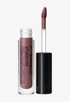 Correcteur de couleur MAC Studio Fix 24 heures en teinte mauve avec tube transparent et bouchon noir, applicateur avec embout en forme de mouche texturé.
