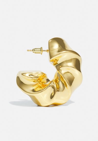Orecchino a spirale in tono oro con una superficie liscia e riflettente e una chiusura a perno. Presenta un design a morbida onda.