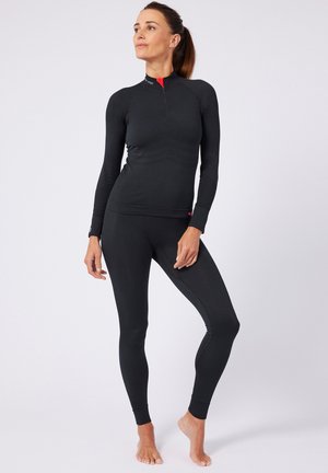 Schwarzes Langarm-Thermooberteil mit einem Halbreißverschluss und strukturiertem Design, kombiniert mit passenden eng sitzenden Leggings. Beide Teile sind feuchtigkeitsableitend.