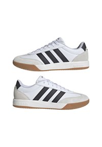 Zapatillas deportivas blancas con rayas negras, parte superior de ante y material sintético, suela de goma, puntera redonda y tacón plano. Marca sutil en el lateral.