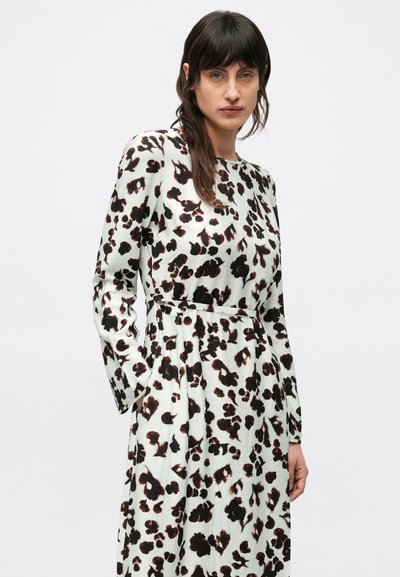 Šaty s dlhým rukávom a priliehavým strihom v svetlo zelenej farbe s hnedými leopardími škvrnami, okrúhlym výstrihom a opaskom v páse. Hladká textúra látky.