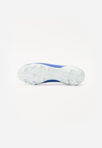 Chausson de football avec une tige bleue et une semelle extérieure blanche dotée de crampons en caoutchouc moulés pour une traction optimale. Texture lisse, design épuré.