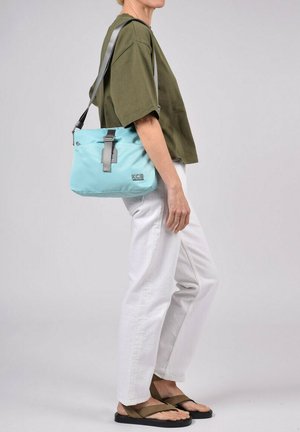 Bolso crossbody de color azul claro, hecho de tela suave, con una correa gris ajustable, detalle de hebilla y un pequeño logo en la parte frontal.