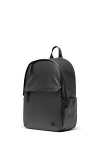 Sac à dos noir avec un extérieur en cuir lisse, forme arrondie, poche zippée à l'avant, poignée supérieure et un branding subtile en bas.