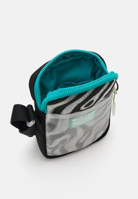 Zebra mintázatú, könnyű anyagból készült tasak, átlátszó előlappal. Turquoise színű zippel és belső béléssel rendelkezik, tartalmaz egy klipszes hurok.