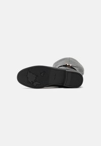 Calzado negro con una suela de goma texturizada que presenta un detalle estampado de un mapamundi. Parte superior suave con un acento decorativo cerca del tobillo.