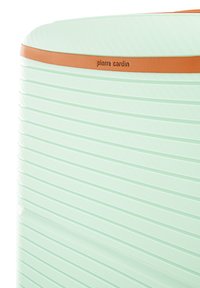 Muntgroene harde koffer met horizontale groeven, voorzien van een bruine leren accentband en een geanodiseerd merkembleem. Glad oppervlak.