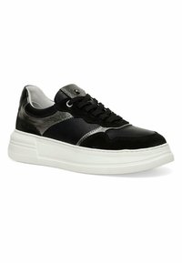 Black and grey sneaker featuring a combination of leather and suede materials, with a thick white rubber sole and textured accents.