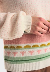 Stickad ulltröja med mjukt, texturerat tyg. Funktioner i pastellfärger: rosa, grön och gräddfärgad med mönster av prickar och blomsterdetaljer.