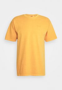 Žluté bavlněné tričko s kulatým výstřihem a krátkými rukávy. Na hrudi má decentní výšivku loga značky. Měkká textura, volný střih.