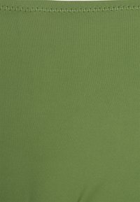 Tecido verde, textura suave, com um padrão estriado. A borda superior possui costura em ziguezague para maior durabilidade.
