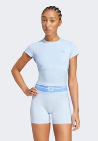 Ensemble de sport bleu clair comprenant un haut ajusté à manches courtes et un short taille haute, avec une texture côtelée et des accents de logo subtils.