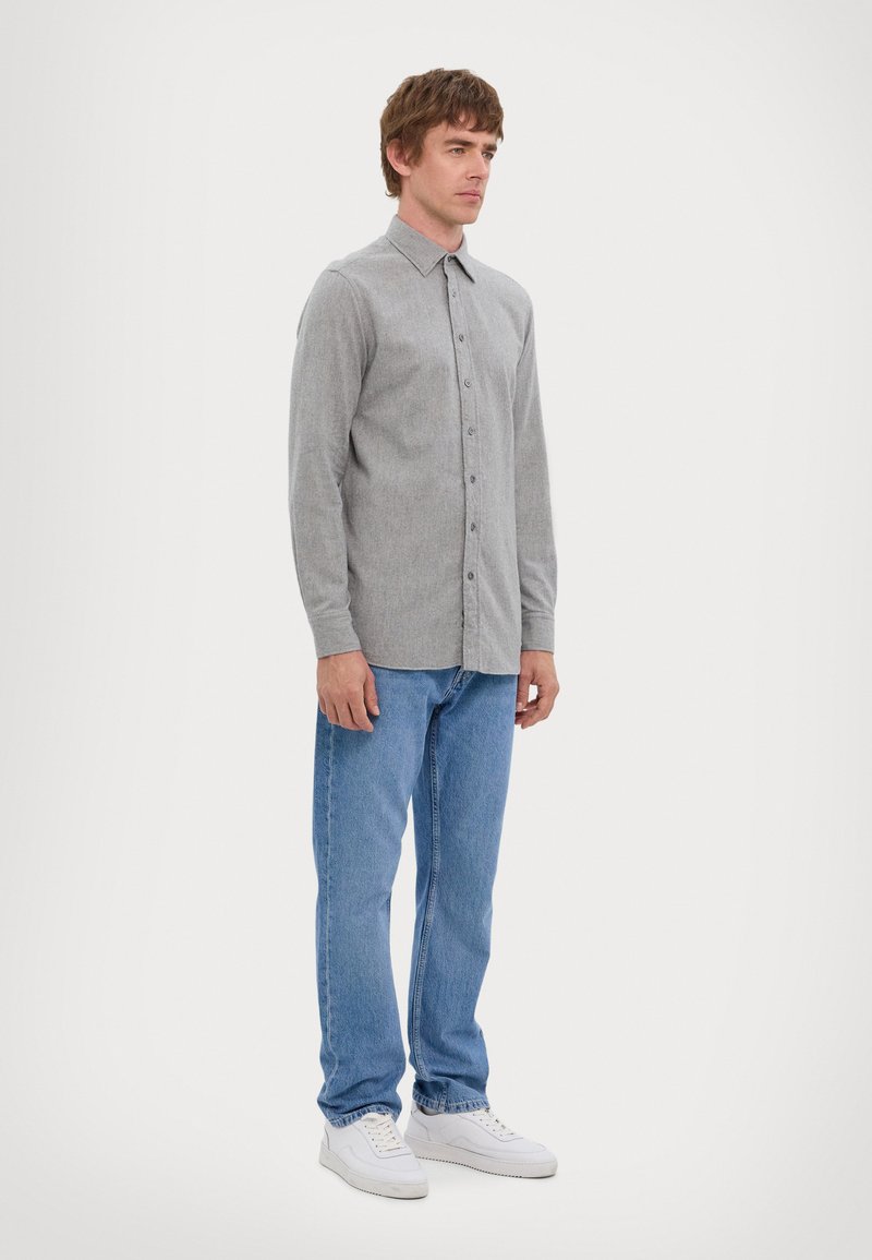 Gray long-sleeve button-up shirt with a collared neck, paired with light blue jeans and white sneakers. The fabric appears textured.