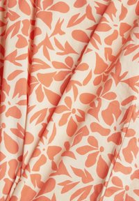 Gemusterter Stoff mit einem pfirsichfarbenen Blumendesign auf einem cremefarbenen Hintergrund, mit glatter Textur und fließendem Fall. Deutliche Blumenformen sind zu erkennen.