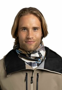 Mehrfarbiger Schlauchschal aus weichem Stoff, mit abstrakten Mustern in Blau, Beige und Grau, unter einer schwarzen Jacke mit Kragen getragen.