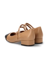 Zapatos de imitación cuero en color marrón claro con puntera negra, tacón cuadrado y detalle de doble correa. Textura suave con un diseño redondeado.