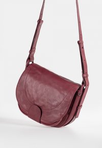 Bordeauxfarbene Leder-Umhängetasche mit abgerundetem Klappe, verstellbarem Riemen und glatter Oberfläche. Verfügt über einen Magnetverschluss und minimale Nahtdetails.