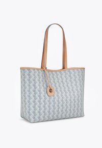 Tote bag met een blauw geweven patroon, lichtbruin leren accenten, twee lange handgrepen en een decoratief label met een gouden embleem.