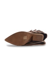 Chaussure en suede marron à bout pointu avec un talon bloc plat, semelle texturée et détail de sangle décorative sur le devant.
