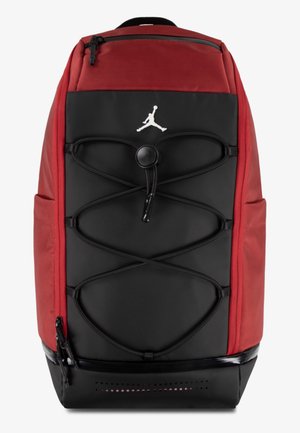 Κόκκινο και μαύρο σακίδιο πλάτης με υφασμάτινη υφή, που διαθέτει σχεδίαση με κορδόνια bungee, τσέπες με φερμουάρ και λευκό λογότυπο Jordan στο μπροστινό μέρος.