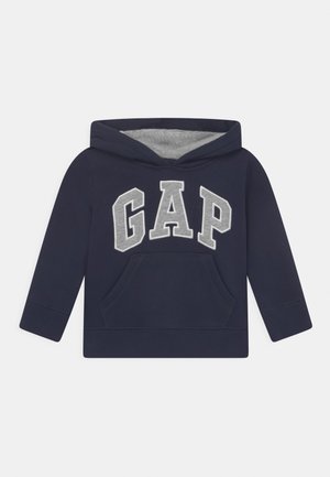 Sudadera con capucha para niño pequeño de azul marino, con forro interior de la capucha en gris, bolsillo tipo canguro en la parte delantera y grandes letras "GAP" en gris across el pecho.