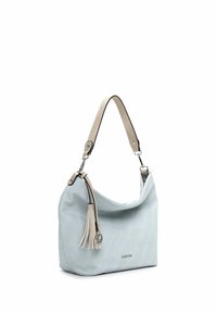 Bolso de tela azul claro con diseño holgado, que cuenta con un tassel desmontable y una asa beige con detalles en negro. Detalle del logo en plata visible.