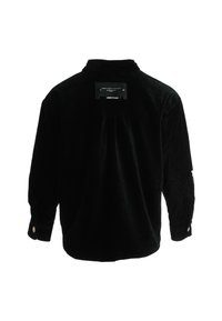 Camisa de pana negra con mangas largas, puños abotonados y una etiqueta en la parte de atrás. Presenta un ajuste holgado y una textura con estrías verticales.