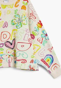 Balta sportinė palaidinė su daugiausiai spalvotomis, rankomis pieštomis raidėmis, gėlėmis ir raštais. Dėl priekinės abrikoso apykaklės ir rankogalių suiais. Matomas "Desigual" etiketė.