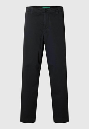 Mustad sirge säärega püksid vööaasade, nööp-kinnituse ja lukuauguga, taustal sile pind.