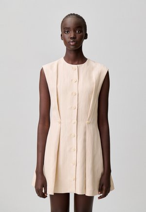 Vestito corto senza maniche in beige chiaro con sottili righe verticali, caratterizzato da uno scollo rotondo e sei bottoni sul davanti.