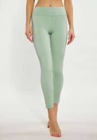 Világoszöld sport leggings sima textúrával, magas derékkal és szűkített fazonnal, amely a bokáig ér kiegészítő részletek nélkül.